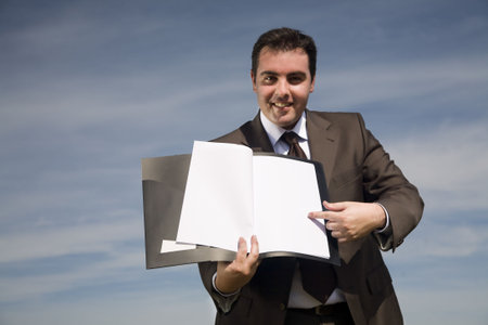 young businessman with corporate binder pointing to blank paper - outdoor environmentの写真素材