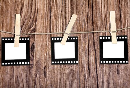 old film blanks hanging on a rope held by clothespins over wood backgroundの写真素材
