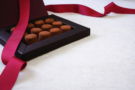 Close up of elegant black box of chocolate truffles, with red ribbon. Valentines Day or romantic celebration concept.の写真素材