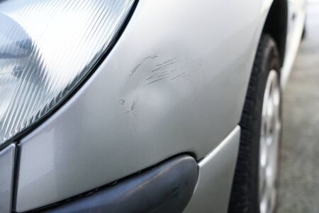 Close up of dent and scratches on side of old silver gray car. Damage from crash accident, parking lot or traffic.の写真素材