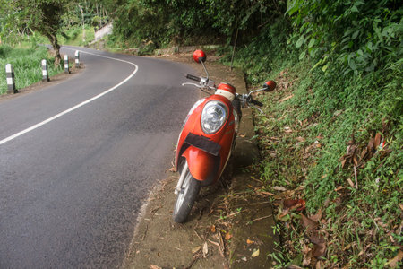 Bali, Indonesia - December 2017: Red Honda scooter. Motorcycle parked in a countryside road.