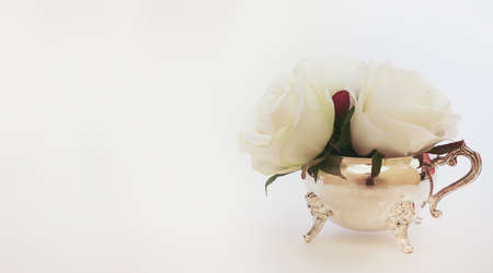 Isolated white flowers inside a silver creamer pot. Concept for afternoon tea, with copy spaceの写真素材