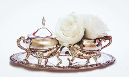 Antique silver creamer and sugar set and decorative white flowers isolated in white background. Afternoon tea concept.の写真素材