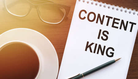 Content is King - text written white notebook with penand cup of coffee on wood table. Digital Business conceptの写真素材