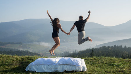 Man and woman jumping on the mountain at dawn. Loving couple resting in the mountains. concept of...