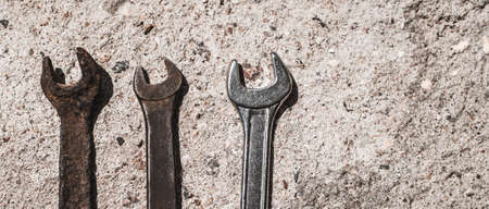 On the cement floor on the surface are different wrenches. Old rusty and shiny new tools on a blackboard background. Mechanics inventoryの写真素材