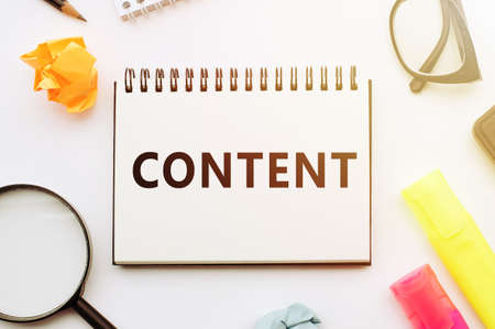 Text CONTENT with notebook pen, glasses and magnifier on white tableの写真素材