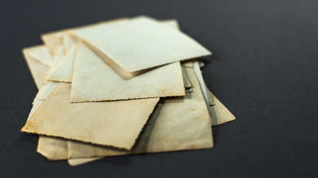 A stack of old photos lying on the table. Mock up blank paper. photo card rumpled and dirty vintage. Retro postcard. Memories of old timesの写真素材