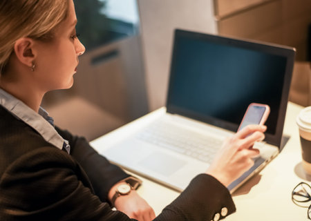 Young businesswoman using phone and tablet computer in coffee shop