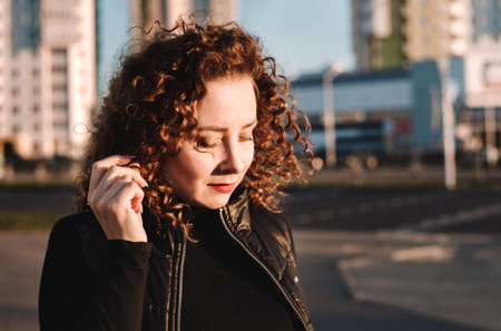 Beautiful girl with curly hair smiles against the backdrop of the city