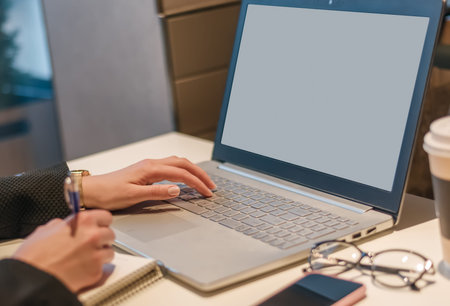 close-up of the hand of a business woman who works on a laptop and writes information into a...