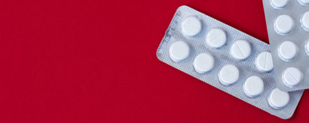 Medicine concept. White tablets are laid out in a line on a red background. Pill red frame isolated....