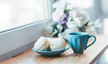 Morning breakfast of coffee and sweet marshmallows on wooden windowsill. Home comfort conceptの写真素材