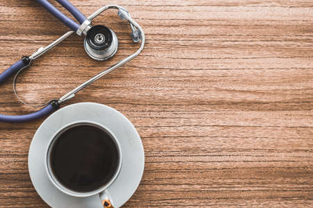 Stethoscope and coffee cup on wooden table, rest time concept for doctors. For your designの写真素材