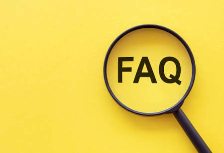 Magnifying glass on wood letters as FAQ abbreviation, frequently asked questions on yellow background.の写真素材