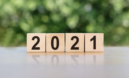 new year concept. font 2021 on wooden cubes on sunrise and bokeh green background