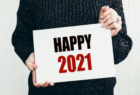 Girl holding a card with text HAPPY 2021. Happy New Year 2021 concept.の写真素材