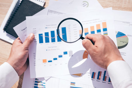 Businessman looking through a magnifying glass to documentsの写真素材