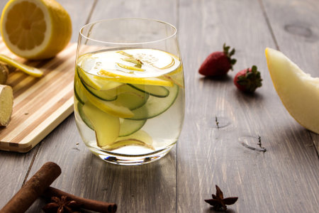 Fresh organic summer ginger cucumber and lemon cocktail on wooden background. Have a drink at the...