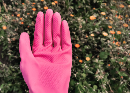 Hand in pink gloves on the plants backgroundの写真素材