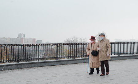 Warszawa, Poland - November 8, 2020: Senior couple in safety mask walking along city streetのeditorial素材