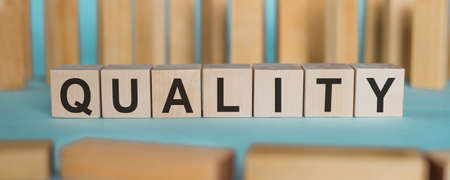 QUALITY word written from wooden blocks on blue backgroundの写真素材