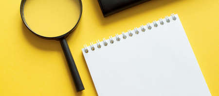 Business concept with notebook, magnifier on yellow backgroundの写真素材