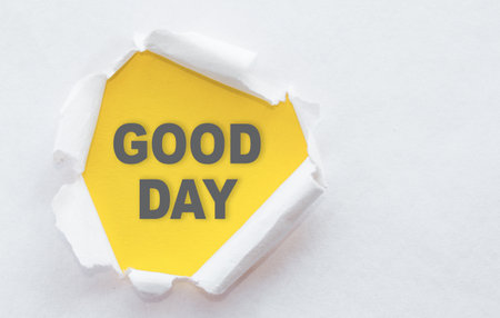 Top view of white torn paper and the text good day on a yellow background.の写真素材