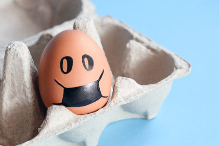 Red egg with painted face wearing a mask in the tray.