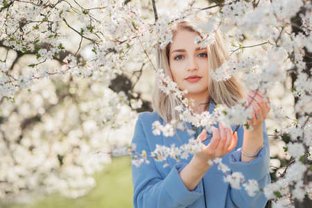 Portrait of young woman in the flowered garden in the spring time. Almond flowers blossomsの写真素材