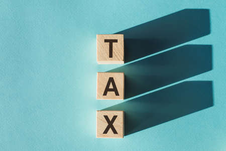 Wooden cubes building word TAX on light blue background.の写真素材