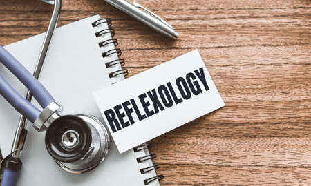 A card with text REFLEXOLOGY on wooden doctor's table.の写真素材