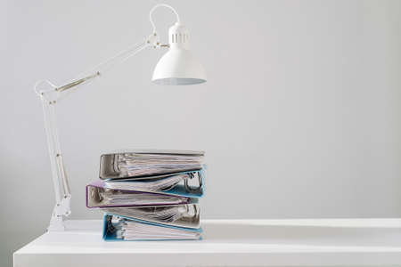 A set of folders on an office desk with lamp. Minimalism business conceptの写真素材