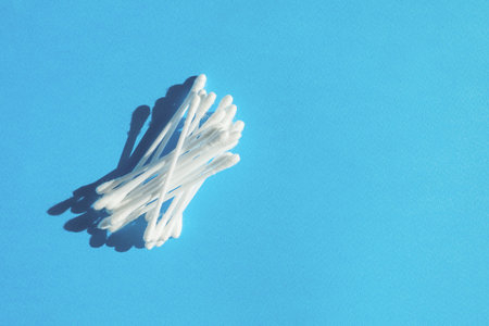 Heap of cotton buds isolated on blue background.