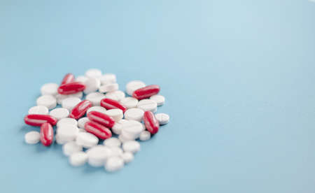 Pile of white and red pills on blue background.の写真素材