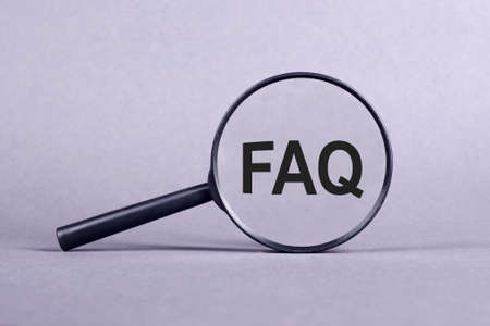 Magnifying glass with FAQ - frequently asked question, inscription on a gray background.の写真素材