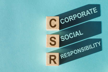 Wooden cubes building word CSR - corporate social responsibility, on light blue background.の写真素材