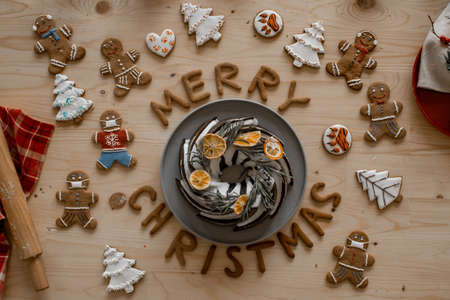 Christmas celebration mood. Traditional homemade christmas cake on a wooden table with ginger gingerbread and cookies in the form of letters of merry Christmasの写真素材