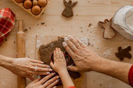 The family cooks homemade ginger cookies for Christmas. Moms, father's hands and son's hands on the dough against the background of the table. Top Viewの写真素材