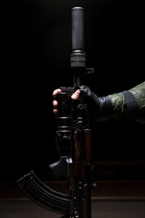 Silenced assault rifle closeup in the hand of the. Male hand hold a assault rifle on black...