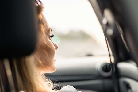 Closeup portrait of a worried car passenger looking at side through the windowの写真素材