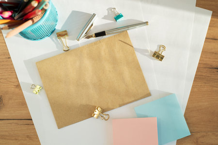 Workspace with clean paper blank, envelope craft, scissors, office supplies on wooden background....