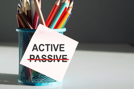 On the desktop with pencils and a yellow sticker with the text ACTIVE above text PASSIVE. business...