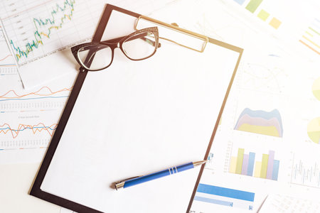 Blue pen and eyeglasses lying on paper clipboard. Mock up for business conceptの写真素材