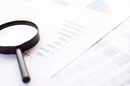 Closeup of magnifying glass on paper background with business chartの写真素材