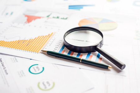 Many charts and magnifying glass. reviewing data. Financial reports and magnifying glass. reflection...