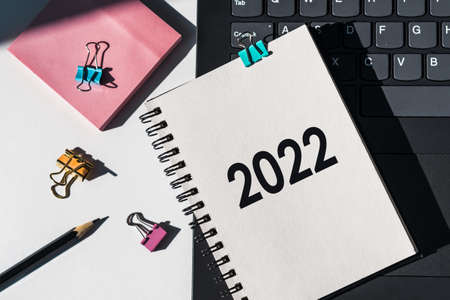 2022 text on white notepad with pencil, staples, notes and keyboard on the backの写真素材