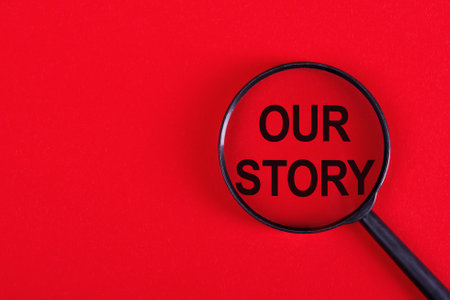 Magnifying glass with the inscription OUR STORY on a red background.の写真素材