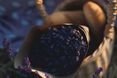 Wicker basket with tasty food and lavender bouquet for romantic picnic in lavender fieldの写真素材