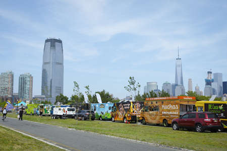 A row of food trucks in park for independence day. Manhattan skyline WTC in background - July 4, 2016, Liberty State Park, NJ, USAのeditorial素材